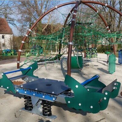 Bild vergr&ouml;&szlig;ern: Spielplatz mit gr�nem Kletterger�st in Form eines Netzes unter einer halbrunden Metallkonstruktion und einer gr�nen Wippe mit Federn in Form von Tieren